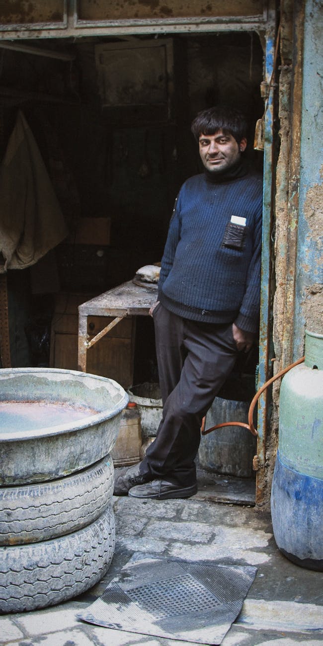 Smiling woman with a towel wrapped around her head, applying foamy face wash in a bathroom.