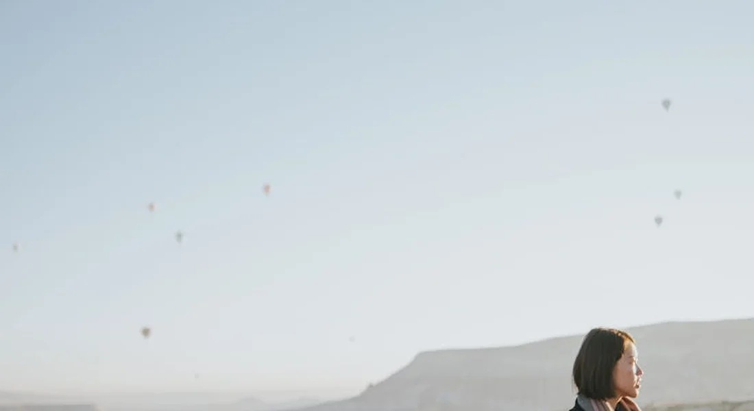 Person with short hair standing outdoors against a bright sky with distant hills, illustrating prep to final sand for automotive clear coat.