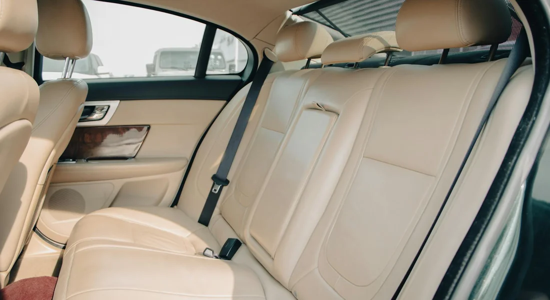Back seat and front passenger seat of a car with beige leather upholstery, showing clean, well-maintained leather.