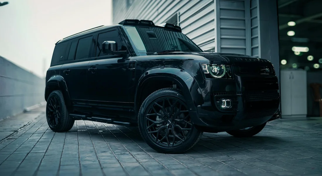 Black SUV with dark tinted windows parked on a tiled urban street, showcasing modern design.