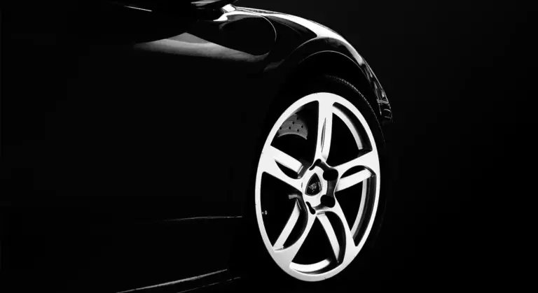 Close-up of a glossy black car showing a silver alloy wheel
