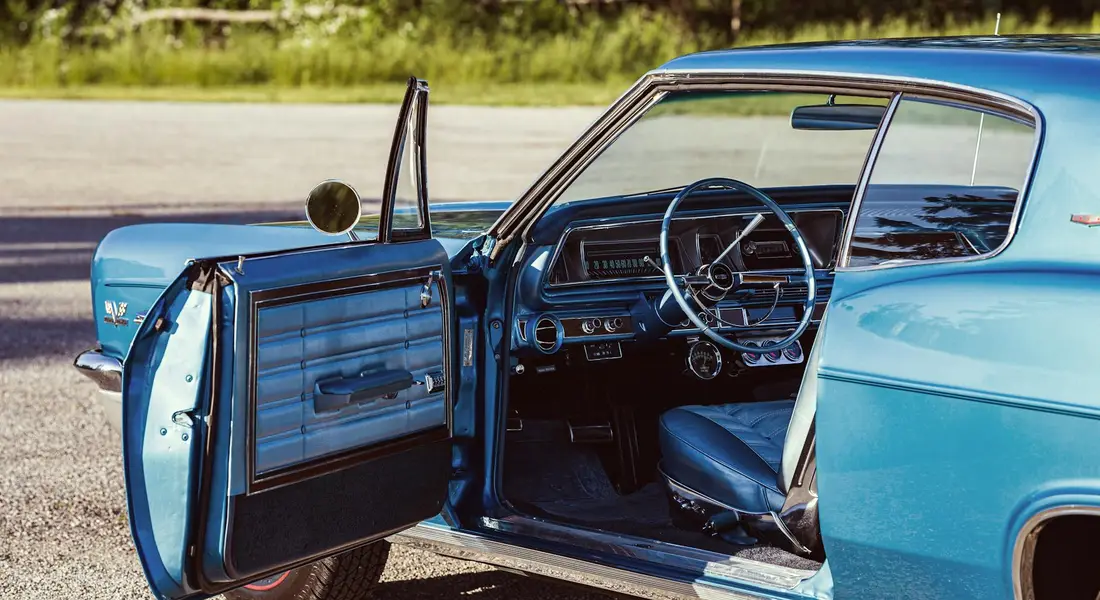 Blue vintage car with the driver's side door open, exposing the interior.