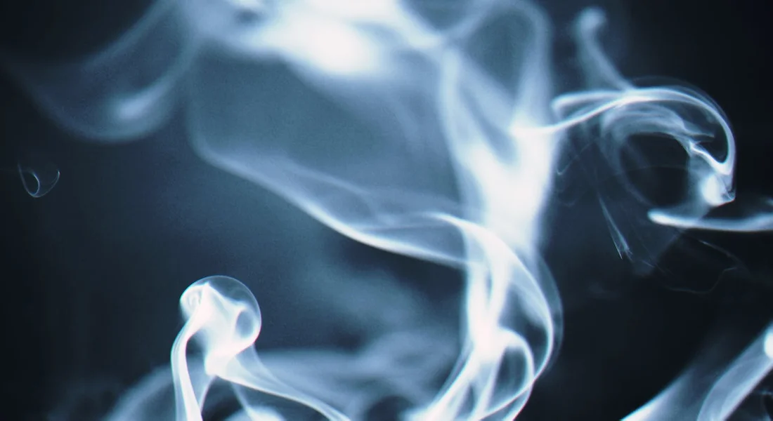 Abstract blue smoke swirls against a dark background
