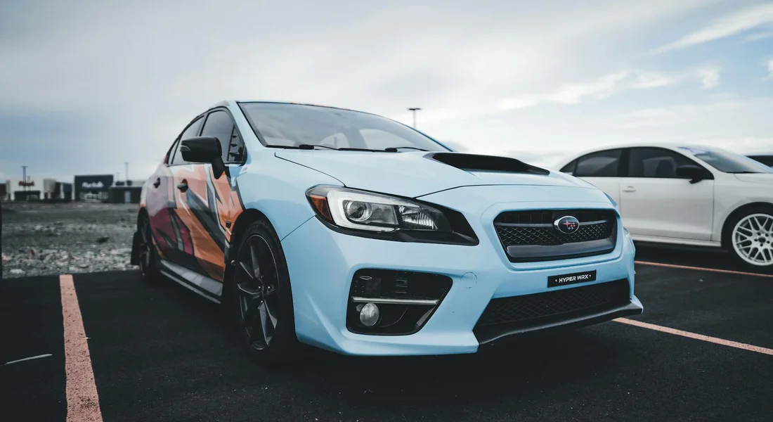 Blue Subaru with a bold vinyl wrap parked in a lot