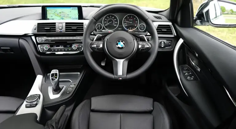 Interior of a BMW car showing the steering wheel, dashboard, and front seats.