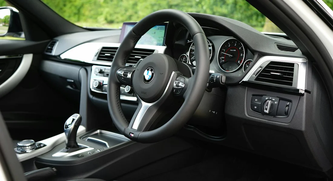Front interior of a BMW car, focusing on the steering wheel and dashboard