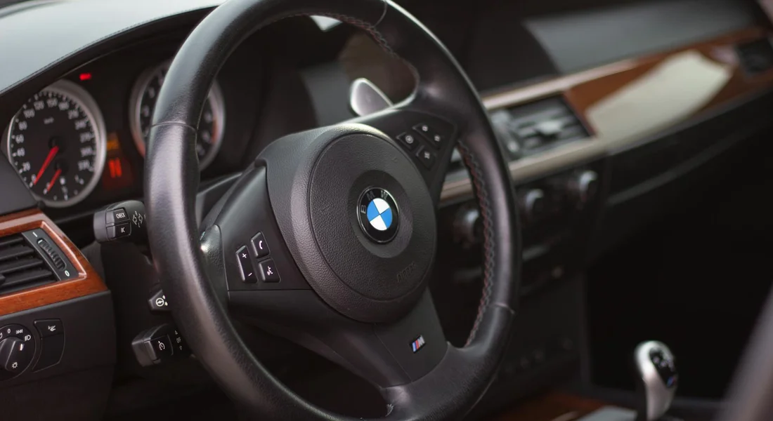 Close-up of a BMW steering wheel inside a car interior.
