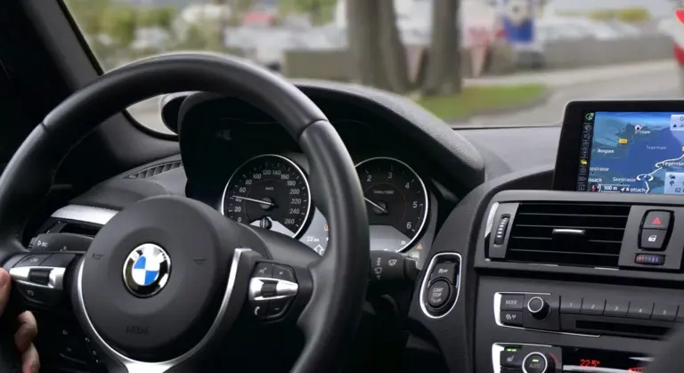Close-up of a car interior showing the steering wheel with BMW emblem and a digital dashboard.