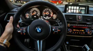 Close-up interior of a BMW showing the steering wheel, instrument cluster, and center console with an infotainment screen.