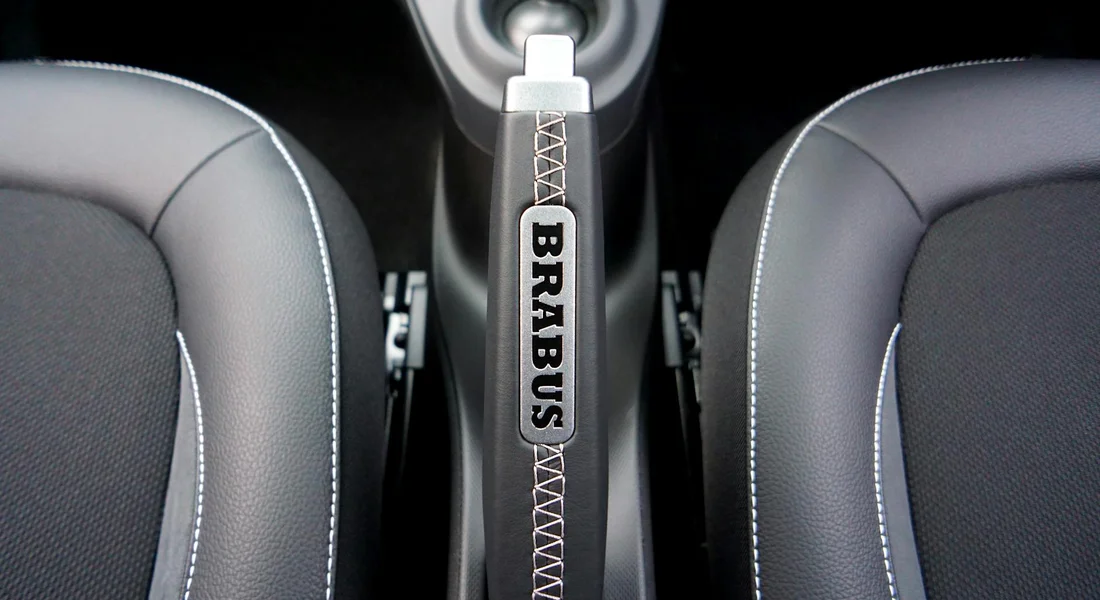 Brabus-branded handbrake between two black leather car seats.