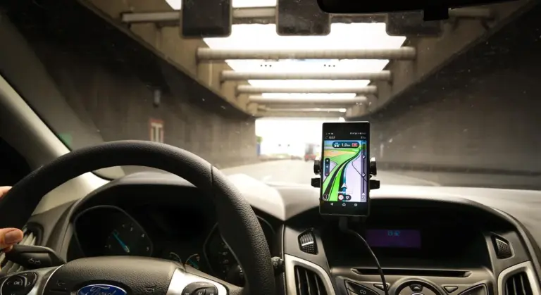 Interior of a car showing the dashboard and steering wheel with a smartphone mounted for navigation, illustrating a clean, well-maintained dashboard.