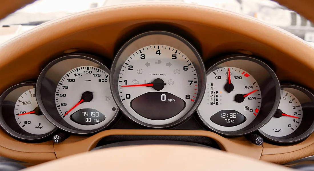 Close-up of a tan car dashboard and instrument cluster.