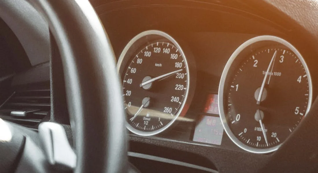 Close-up of a car's dashboard with speedometer and tachometer, illustrating the interior environment.