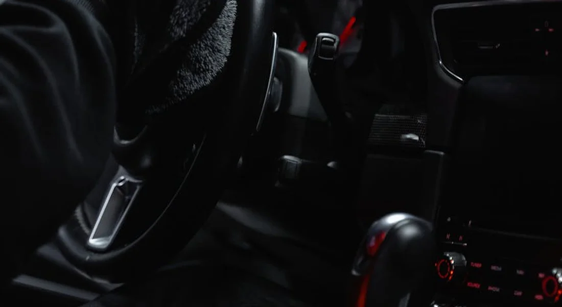 Dimly lit car interior showing the dashboard and center console, suggesting preparation for cleaning.