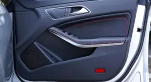 Close-up of a car's interior door panel with controls, showing clean fabric and stitching.