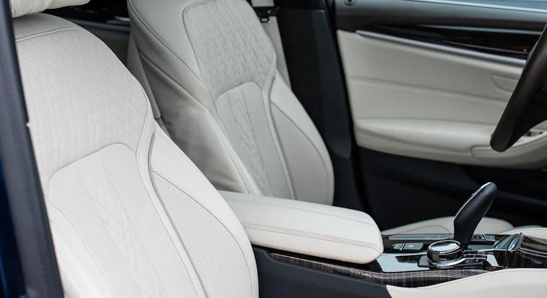 Light beige leather car seats and a center console, prepared for a deep cleaning of upholstery and carpets.