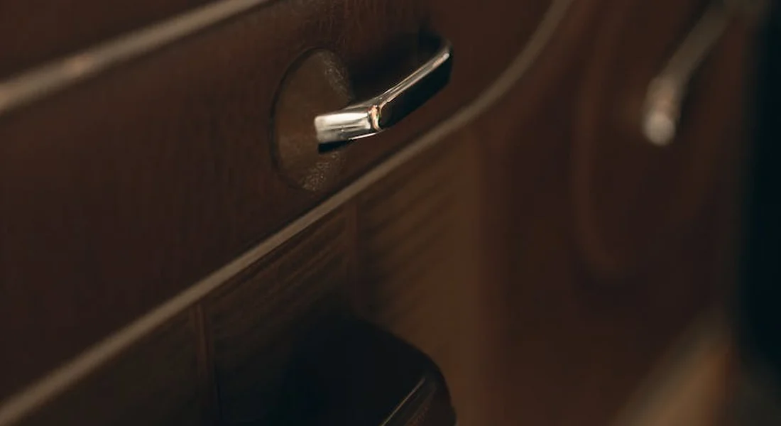 Close-up of a car interior door handle set into a brown plastic panel