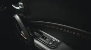 Close-up of a car's interior door panel featuring window controls and stitched leather