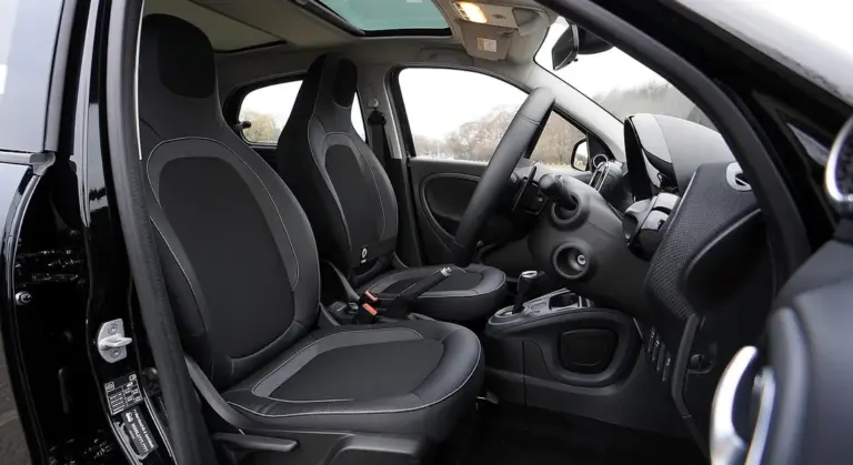 Interior view of a car showing the front seats, steering wheel, dashboard, and door panels.