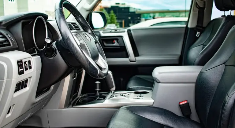 Interior view of a modern car showing the driver's seat, steering wheel, center console, and front passenger seat.