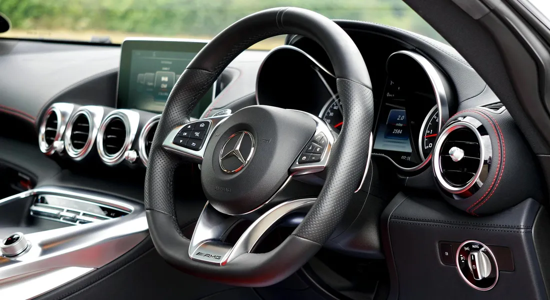 Close-up view of a luxury car interior featuring a leather-wrapped steering wheel and round chrome air vents.