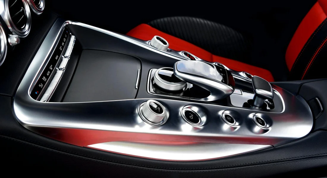 Close-up of a modern car interior center console with chrome controls and red accents, showing clean surfaces that can harbor moisture where mold can grow.