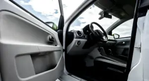 Open-door view of a car interior showing the dashboard, steering wheel, and front seats
