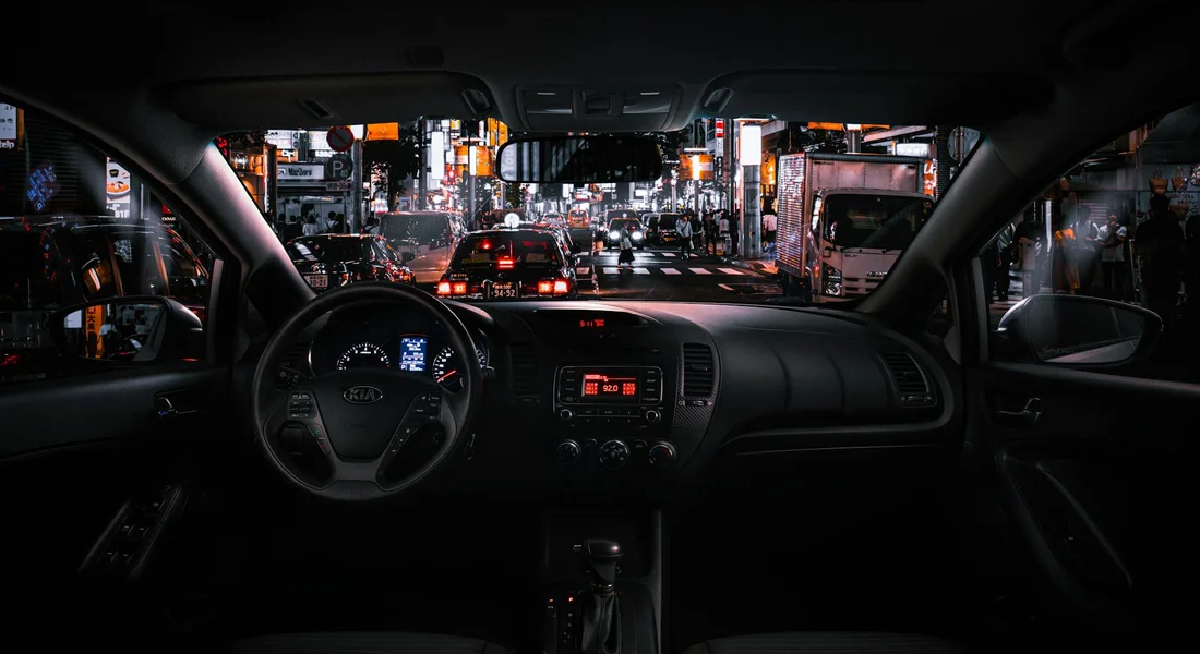 Interior of a car at night with city lights through the windshield; the fabric headliner is highlighted as a delicate ceiling surface.