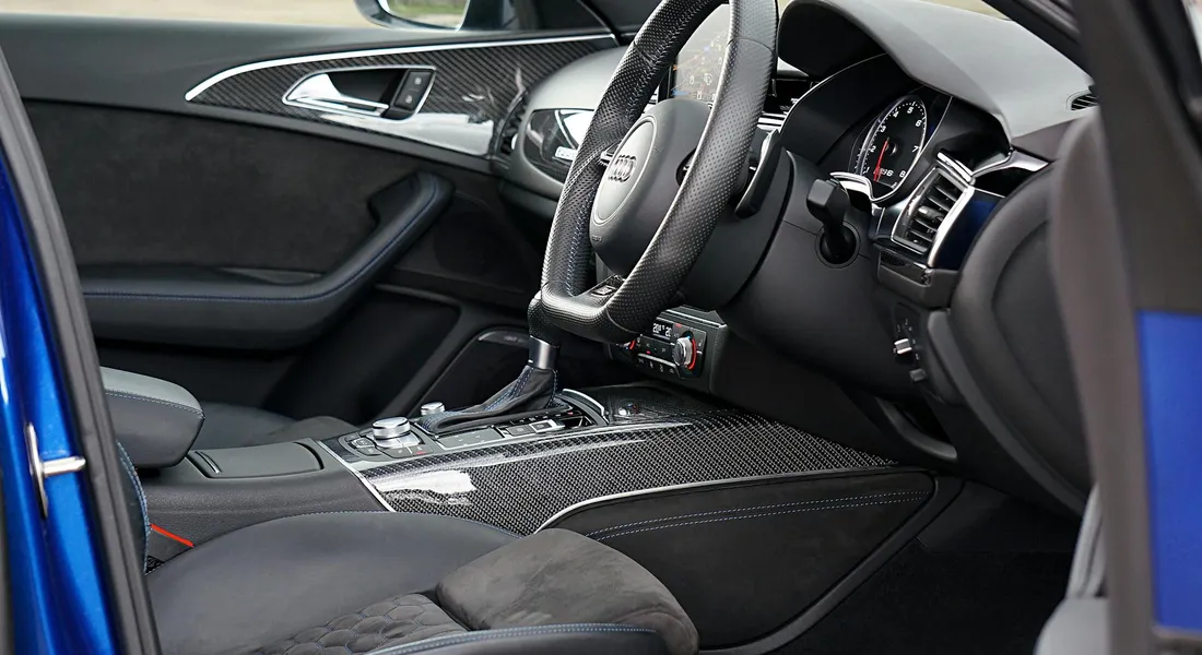 Interior of a modern car with a clean dashboard and carbon-fiber trim, showing the cabin where persistent odors may linger.