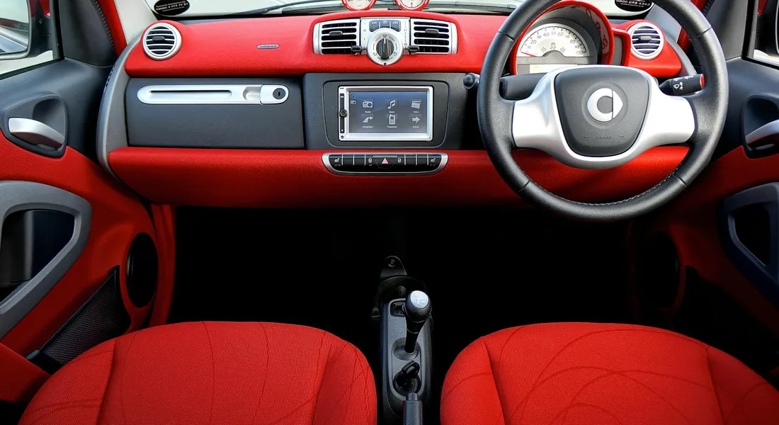 Interior view of a red car showing the dashboard, steering wheel, and red seats