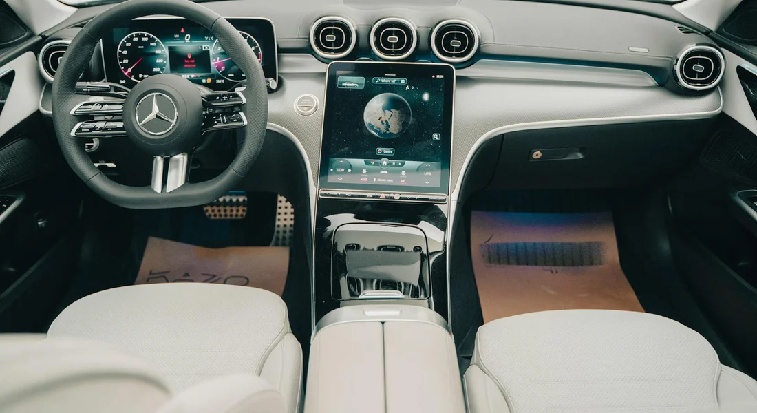 Top-down view of a clean luxury car interior with white seats, a central touchscreen, and a sleek dashboard.