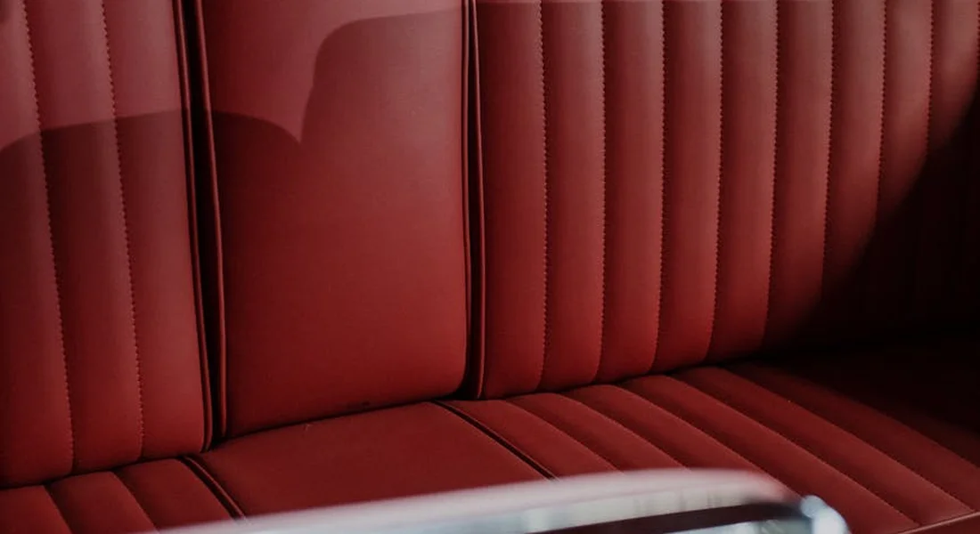 Red leather car interior seats, representing the car interior where odor removal work will take place.