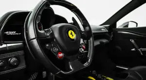 Close-up of a Ferrari interior steering wheel with carbon fiber trim and glossy panels, highlighting interior plastic surfaces prone to scratches.