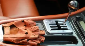 Leather driving glove resting on the center console next to the gear shifter inside a car interior.