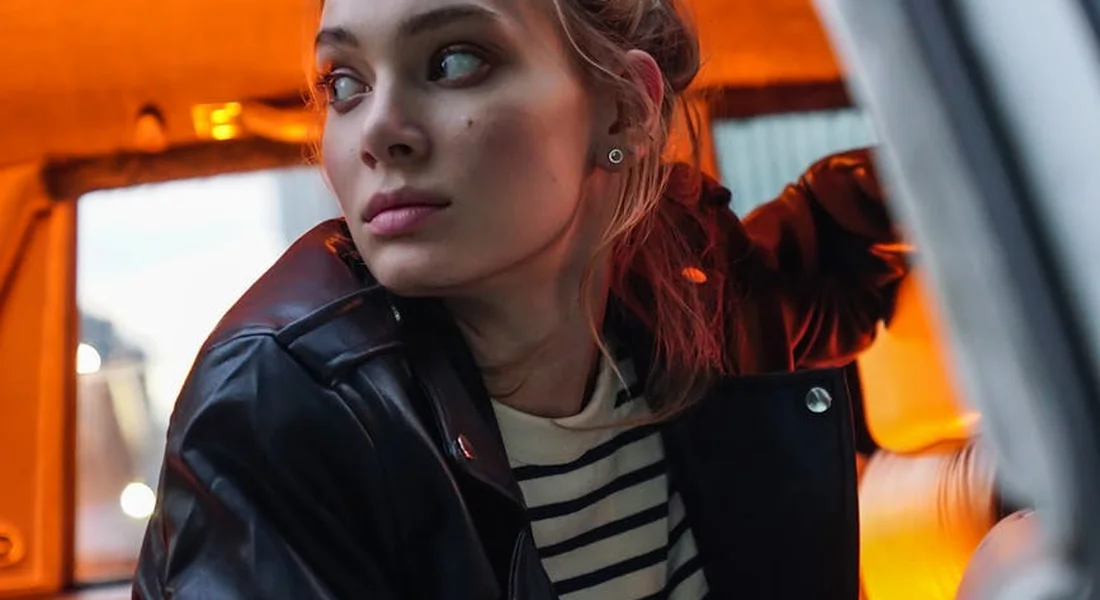 Portrait of a woman in a car with warm orange interior lighting, looking to the side.