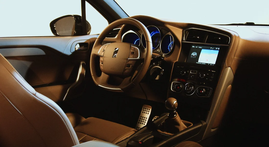 Inside a modern car with tan upholstery, showing the steering wheel, dashboard, and center console.