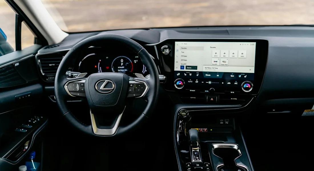 Interior view of a luxury car showing the steering wheel, digital dashboard, and center console.