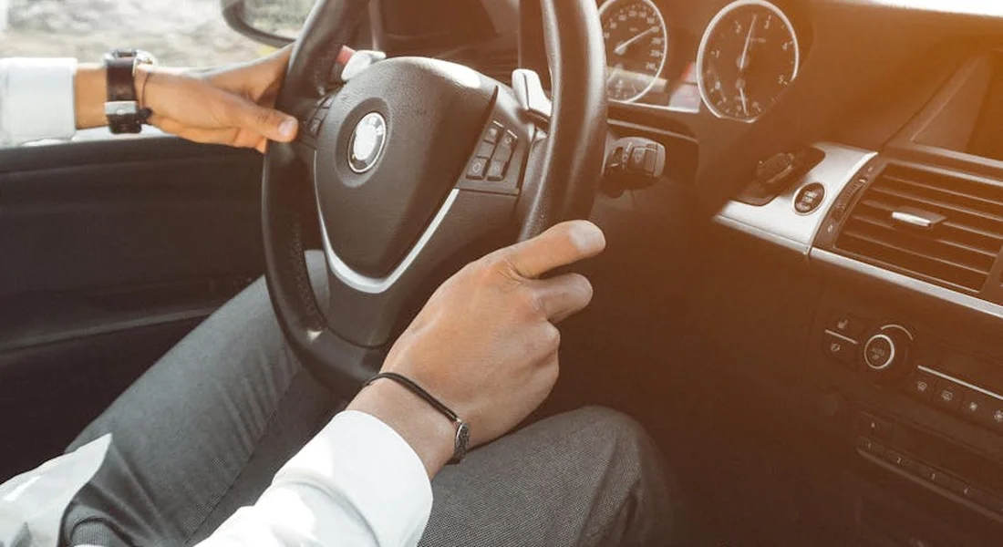 Close-up of a driver's hands on the steering wheel inside a car interior.