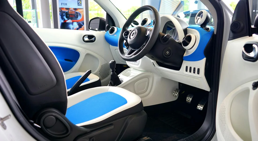 Compact car interior with blue and white seats and dashboard, prepared for cleaning