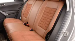 Back seat area of a car with brown leather upholstery.