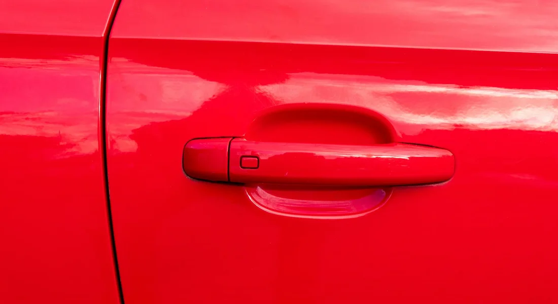 Close-up of a bright red car door and door handle
