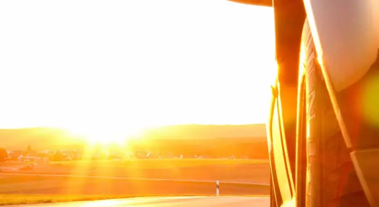Close-up of a car's exterior in bright sunset light with strong glare on the paint