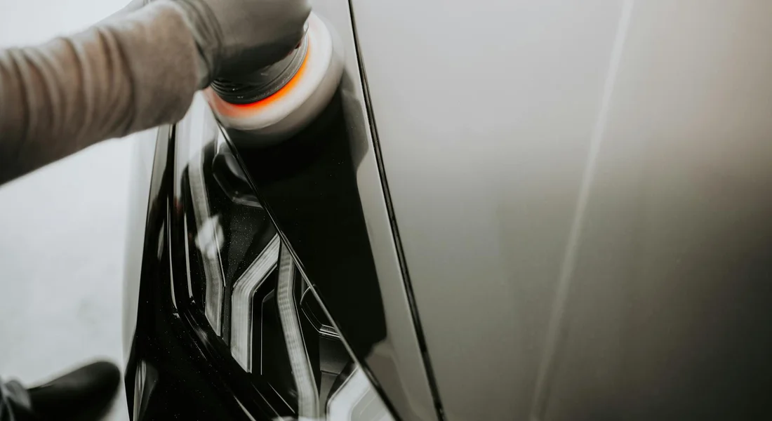 A person using a polishing machine to buff a car's painted surface
