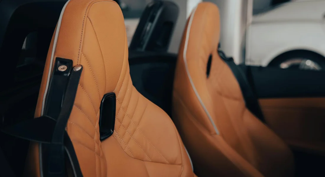 Close-up of tan leather car seats with visible stitching inside a vehicle.