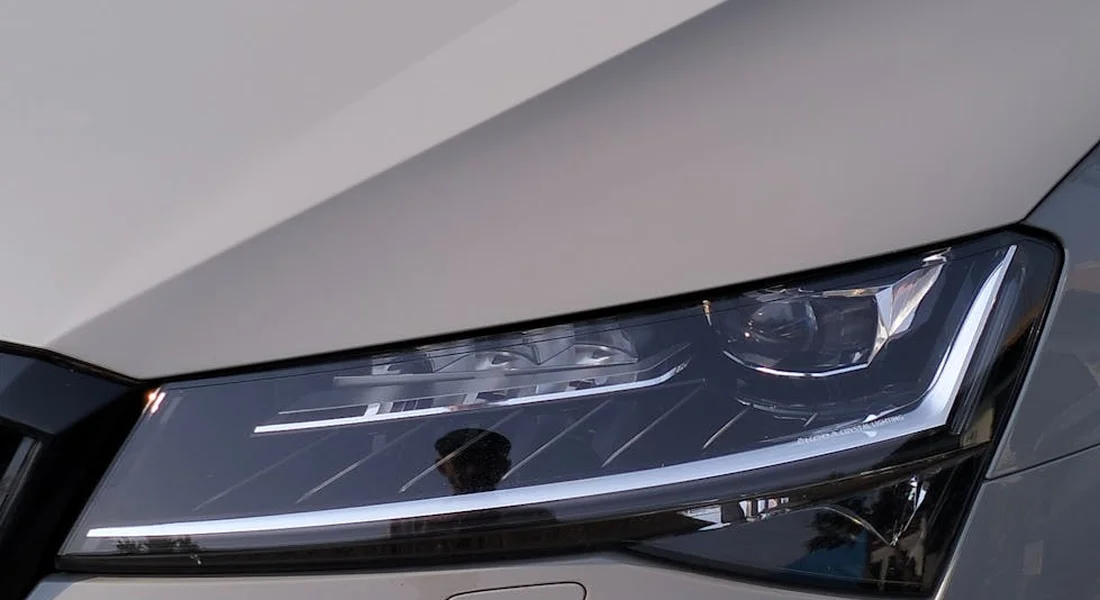 Close-up of a modern car's headlight and surrounding exterior trim on a silver-gray body.