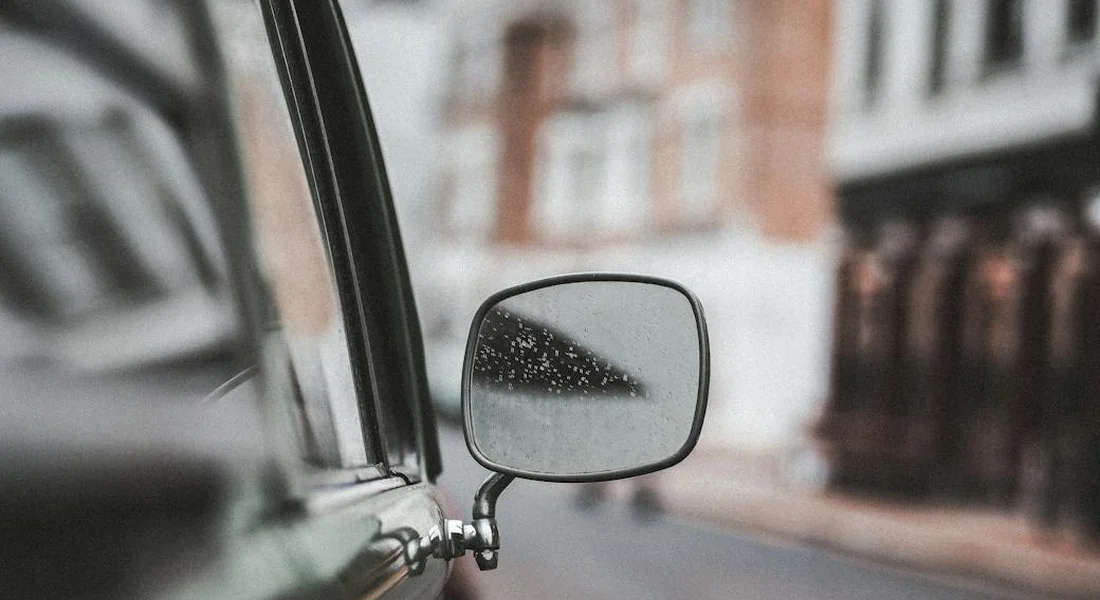 Close-up of a car's side mirror with water droplets on its surface.