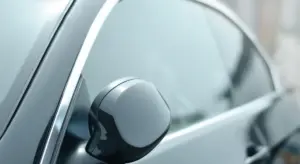 Close-up of a car's side window and side mirror, showing the glass surfaces to be cleaned.