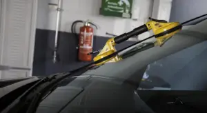 Windshield in a repair shop with a yellow repair tool attached to the glass.
