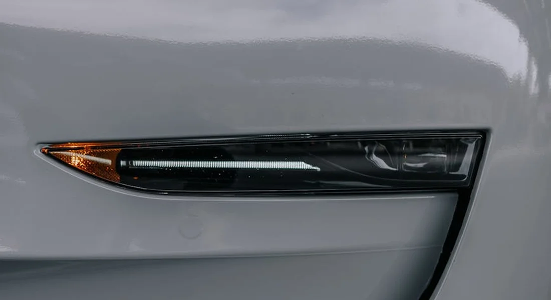Close-up of a gray car bumper with a faint scratch along the edge near the headlight.