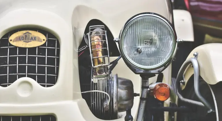 Close-up of a vintage car's headlight and front grille